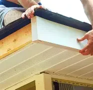 fascia & soffit Two hands installing a white soffit board on a roof edge.